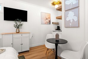 Una habitación moderna con cama, escritorio, silla, televisión y obras de arte en las paredes.