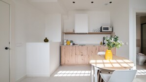 Een kleine keuken met een houten aanrecht, een magnetron en een vaas met bloemen op de tafel.