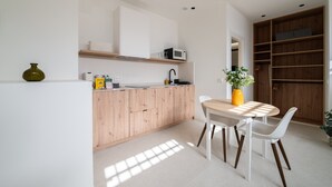Een moderne keuken met houten kastjes, een wit aanrechtblad en een eethoek met een tafel en stoelen.