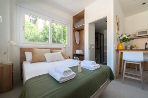A bedroom with a bed, a desk, a shower, and a view of greenery outside. - GuestReady - Estudio super acogedor en Madrid (Madrid)