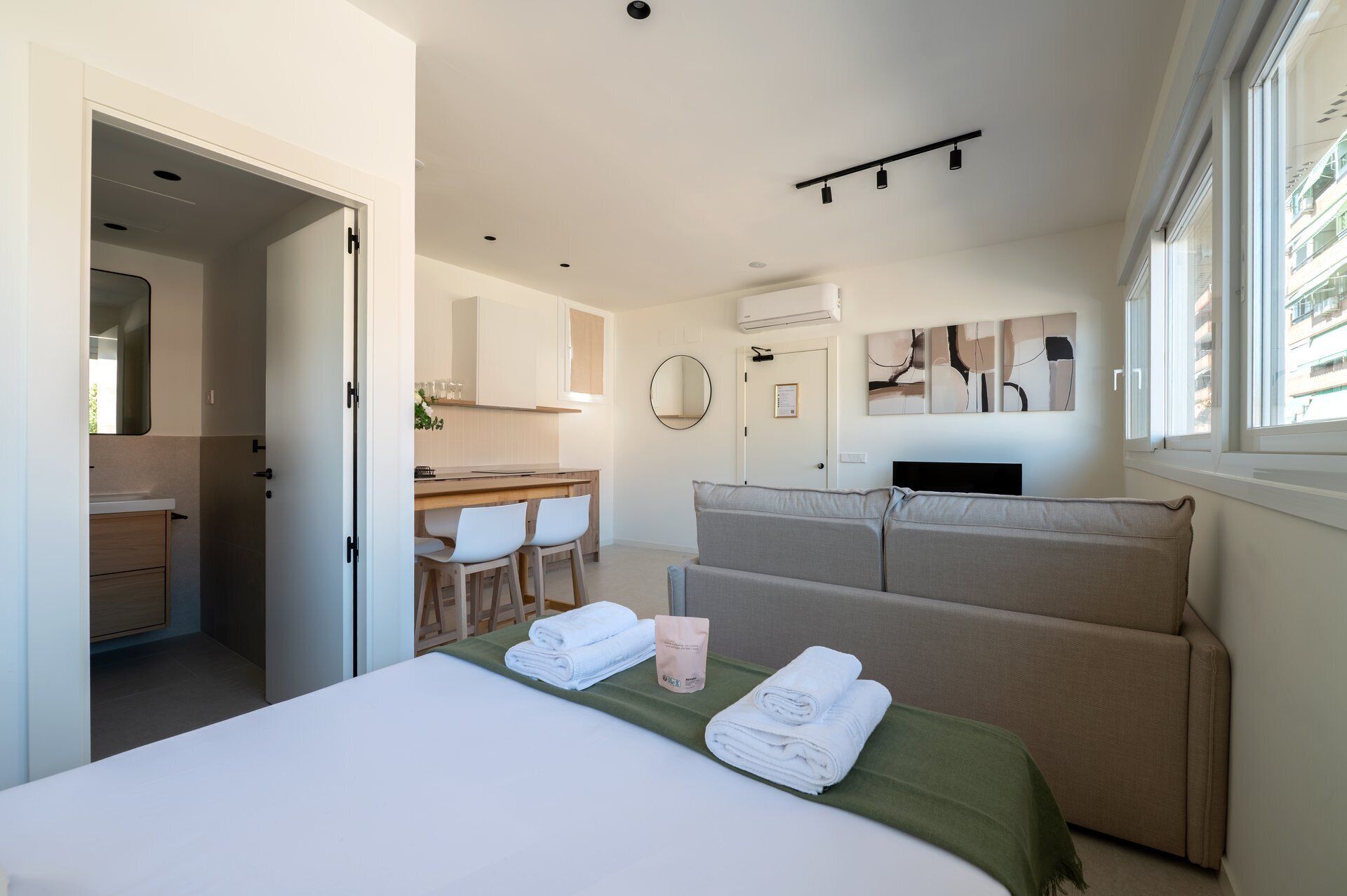 Ein modernes Hotelzimmer mit Bett, einer Sitzecke, einem Essbereich und einem Badezimmer.
