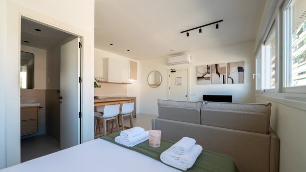 Ein modernes Hotelzimmer mit Bett, einer Sitzecke, einem Essbereich und einem Badezimmer.