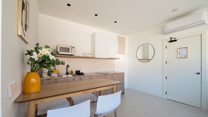 Eine moderne Küche mit einem Holztisch, weißen Stühlen, einer Mikrowelle und einem Blumenstrauß.