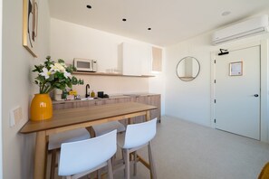 A modern kitchen with a wooden table, white chairs, a microwave, and a vase of flowers. - GuestReady - Estudio super acogedor en Madrid (Madrid)
