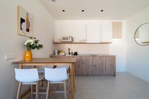 A modern kitchen with a wooden countertop, white cabinets, a microwave, and a vase with flowers on the table. - GuestReady - Estudio super acogedor en Madrid (Madrid)