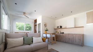 Ein modernes Wohnzimmer mit einer Couch, einem Couchtisch und einer Küchenzeile mit Holdekor und einer Mikrowelle.