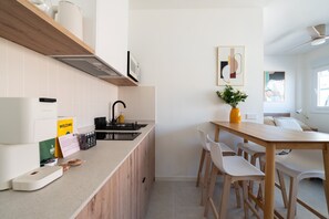 Eine moderne Küche mit Einbauherd, Spüle und Essbereich mit Holztisch und weißen Stühlen.