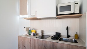 Moderni keittiö, jossa on mikroaaltouuni, leivänpaahdin, pesuallas ja puukehikoiset kaapit.