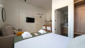 A hotel room with a bed, a TV, a desk, and a bathroom.