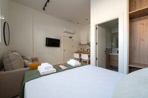 A hotel room with a bed, a TV, a desk, and a bathroom.