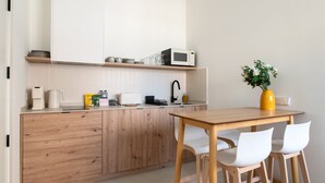 A modern kitchen with wooden cabinets, a microwave, and a dining area with a table and chairs.