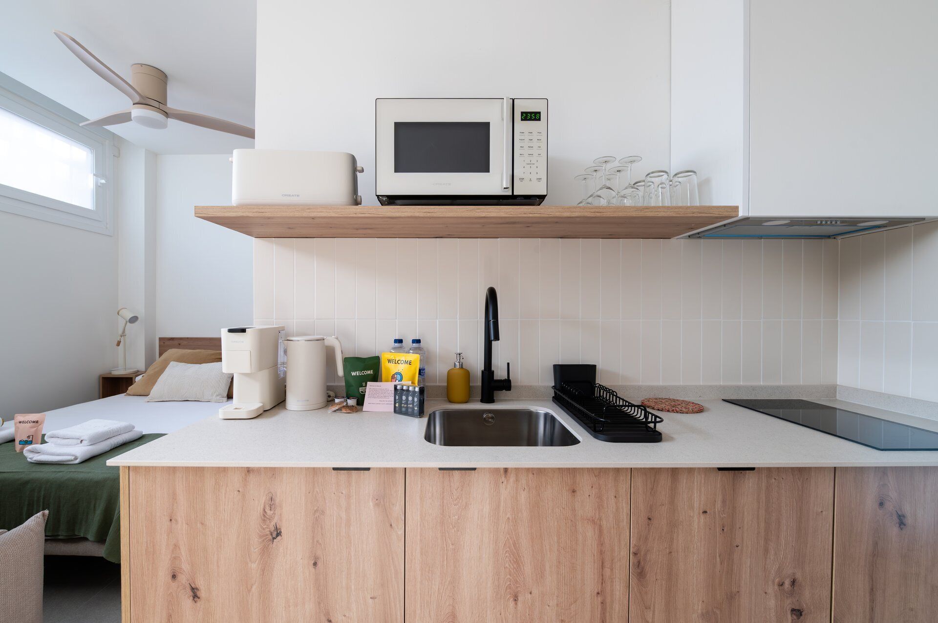 Una cocina moderna con microondas integrado, cafetera y lavabo.