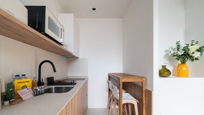 Een moderne keuken met een houten aanrecht, een ingebouwde magnetron, een spoelbak en een kleine eethoek met stoelen.