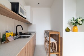 Een moderne keuken met een houten aanrecht, een ingebouwde magnetron, een spoelbak en een kleine eethoek met stoelen.