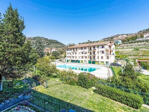 A hotel with a swimming pool, surrounded by greenery and hills.