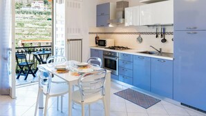 A modern kitchen with blue cabinets, a gas stove, and a dining area with a table and chairs.