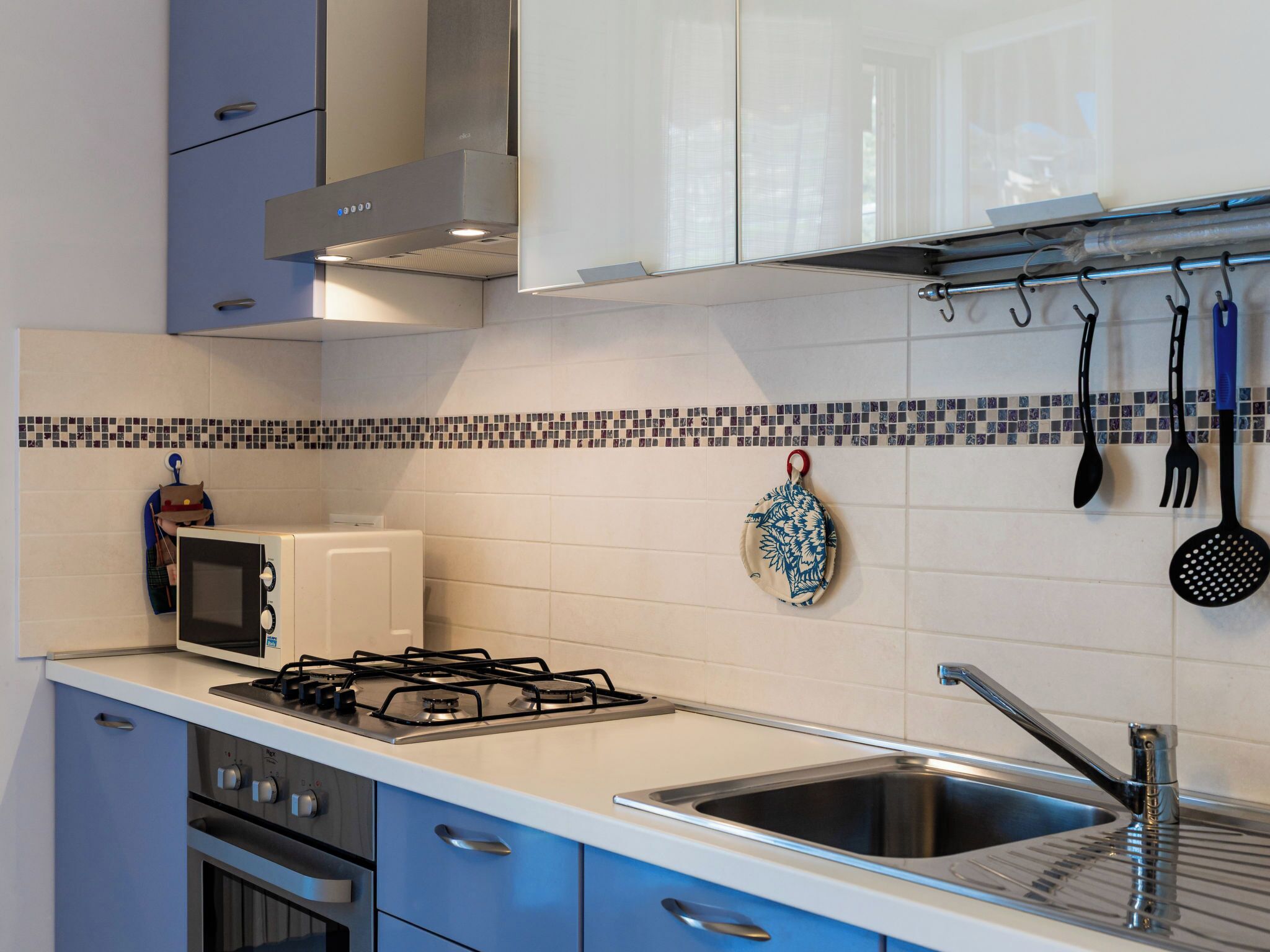 Una cucina moderna con piano cottura a gas, forno a microonde e lavello in acciaio inossidabile.