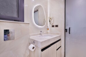 A bathroom with a marble sink, a mirror, a hairdryer, and a toilet paper holder. - Luxury Rooftop Apartment in VYE Sodic New Zayed – Premium Stay, Pet-Friendly! (Giza Governorate)