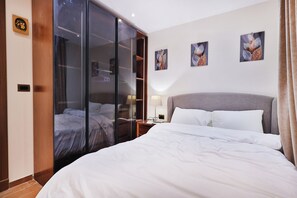 A hotel room with a bed, a wardrobe, a nightstand, and wall art. - Luxury Rooftop Apartment in VYE Sodic New Zayed – Premium Stay, Pet-Friendly! (Giza Governorate)