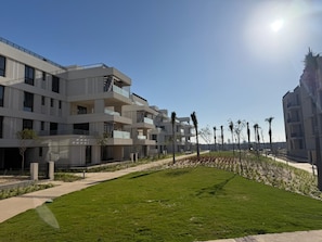 A modern multi-story building with balconies, a well-maintained lawn, and a clear sky. - Luxury Rooftop Apartment in VYE Sodic New Zayed – Premium Stay, Pet-Friendly! (Giza Governorate)