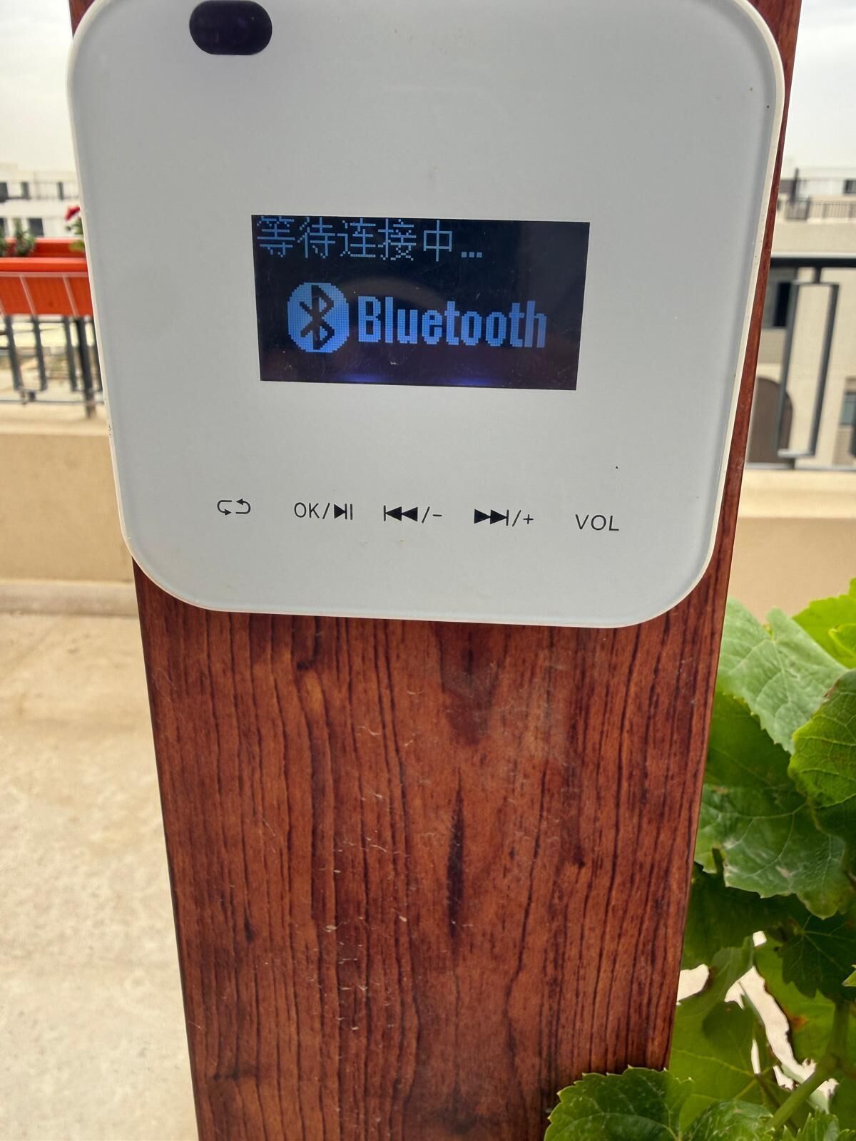 A smartphone with a Bluetooth symbol and Chinese characters, mounted on a wooden post.