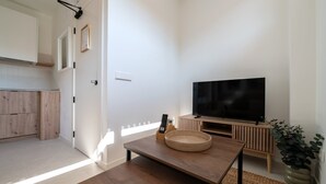 Ein modernes Wohnzimmer mit Fernseher, Holzmöbeln und einer Pflanze.