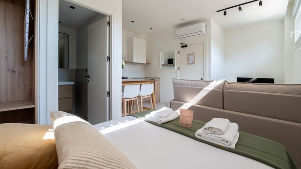Ein Hotelzimmer mit Bett, Sofa, Schreibtisch und einer Küchenzeile.