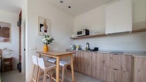 Eine moderne Küche mit Holzschränken, einer weißen Arbeitsplatte und einem Essbereich mit weißen Stühlen.