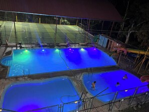 Ein Poolbereich mit mehreren Pools, einer überdachten Sitzgelegenheit und einem kleinen Gebäude.