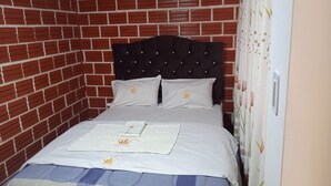 A single bed with a dark headboard, white bedding, and a small towel with a logo. - La Jungla del Rey (Shipasbamba)