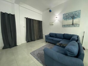 A living room with a blue sofa, a grey rug, and a painting of a tree on the wall. - Serene 2-bedroom apartment with AC in Saint David (Saint David)