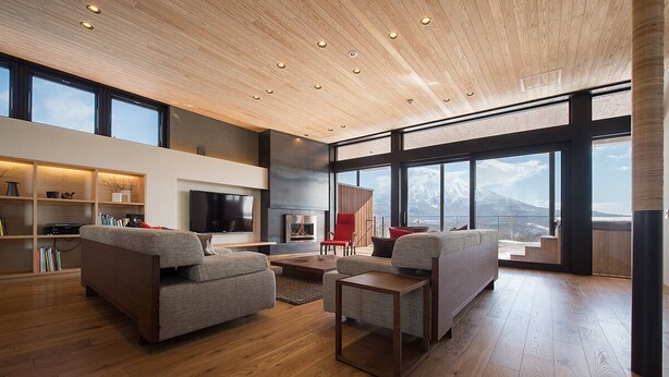 Un salon moderne doté d’une cheminée, de grandes fenêtres et d’un plafond en bois.