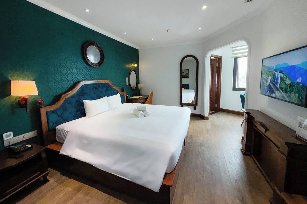 Una camera d'albergo con un letto grande, una TV, una scrivania e uno specchio.