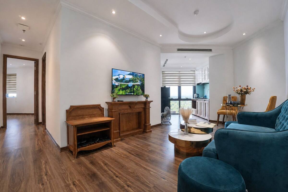 Un ampio soggiorno con un'elegante parete porta TV in legno, un divano blu e un televisore fissato alla parete.