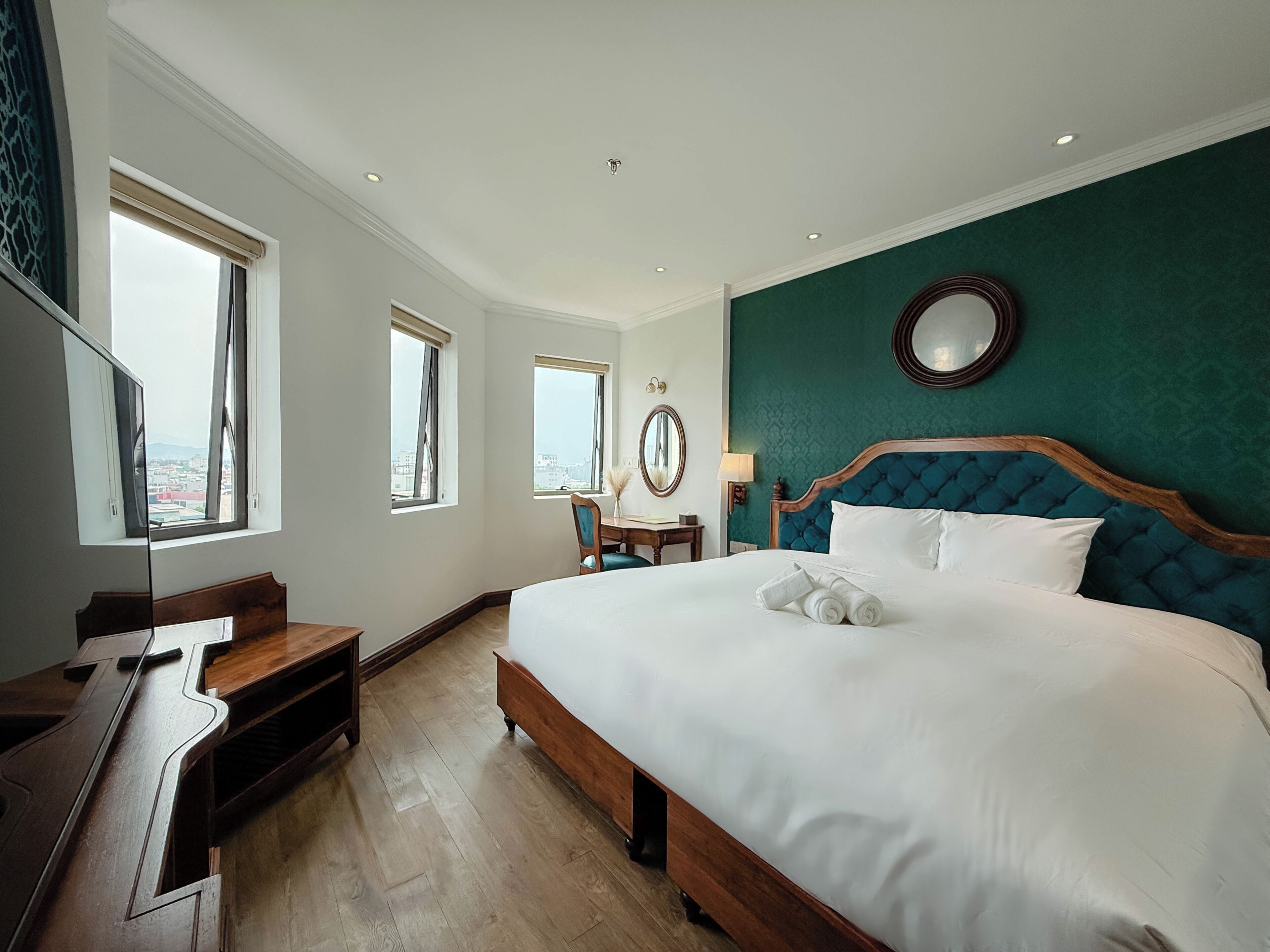 Ein Hotelzimmer mit Bett, Schreibtisch, Stuhl und Spiegel.