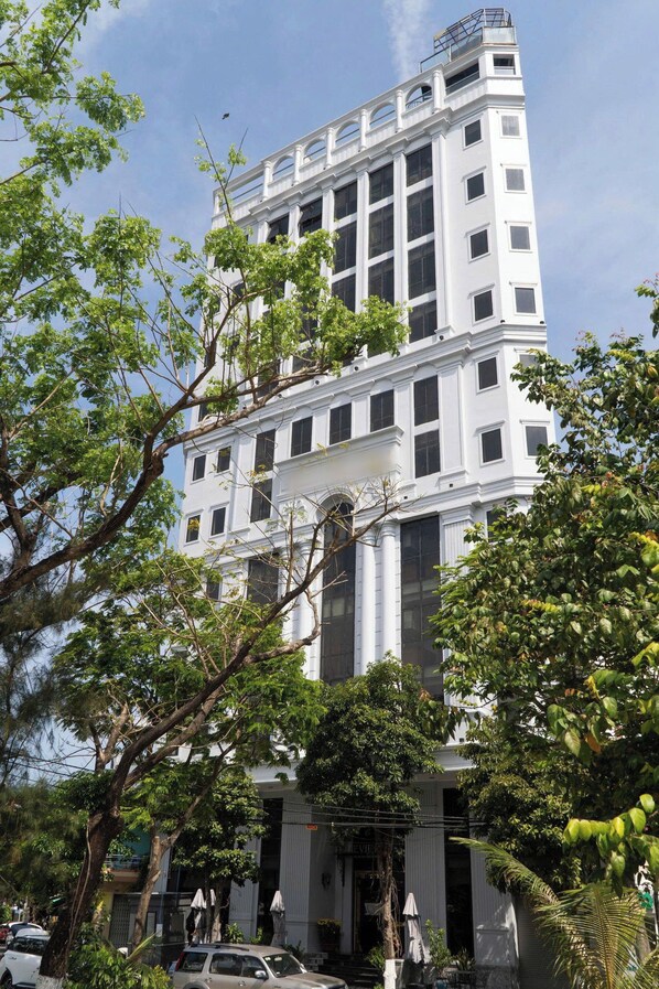 Un immeuble à plusieurs étages, de style architectural classique, qui se distingue par une entrée imposante, ornée de colonnes, et par des balcons situés aux étages supérieurs.