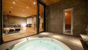Ein modernes Badezimmer mit einer großen Badewanne, einer Duschkabine und einem gläsernen Wohnbereich mit Sofa und Essbereich.