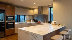 Eine moderne Küche mit einer Marmorinsel, Holzschränken und einem eingebauten Ofen.