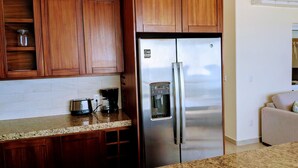 Una cocina con armarios de madera, un refrigerador de acero inoxidable, una cafetera y un dispensador de agua.