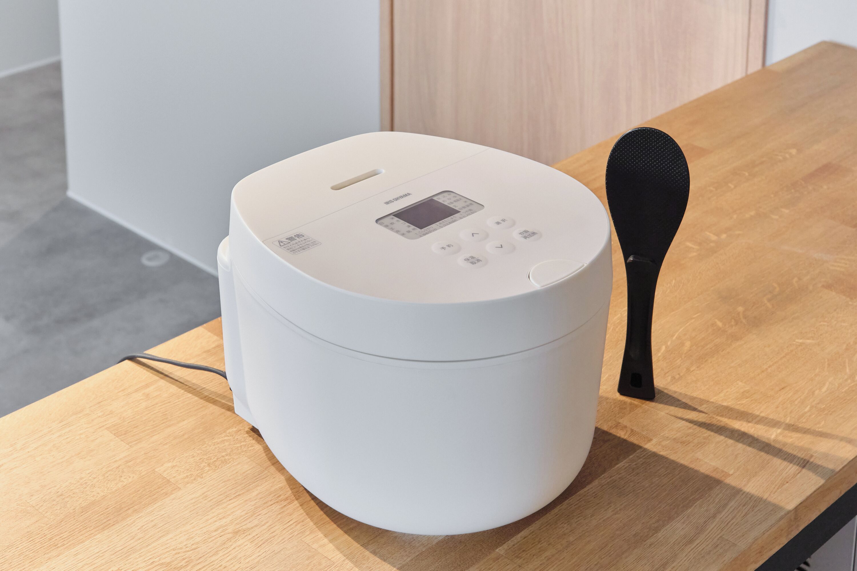 A white appliance on a wooden table with a control panel and a black handle.