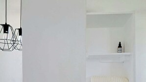 Ein minimalistisch eingerichteter Raum mit Schachbrettmuster auf dem Boden, einem Schachbrett, einer Pendelleuchte und weißen Regalen.