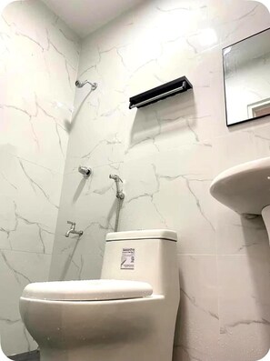Une salle de bain avec des toilettes, une douche et un lavabo.