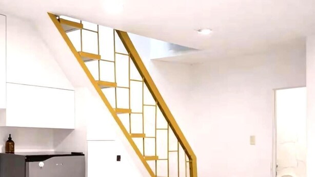 Eine moderne Küche mit einem eingebauten Kühlschrank, einer Holztreppe und einer weißen Arbeitsplatte.