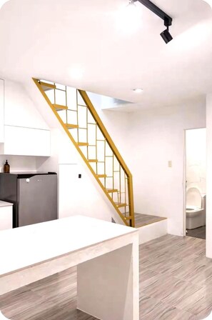Eine moderne Küche mit einem eingebauten Kühlschrank, einer Holztreppe und einer weißen Arbeitsplatte.
