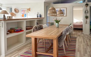 Ein Essbereich mit einem Holztisch, Stühlen und einem Streifen Teppich.