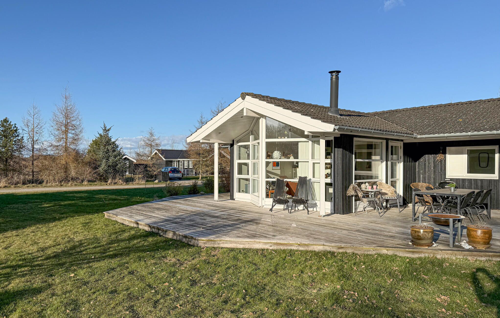 A house with a deck, a chimney, and a car parked outside.