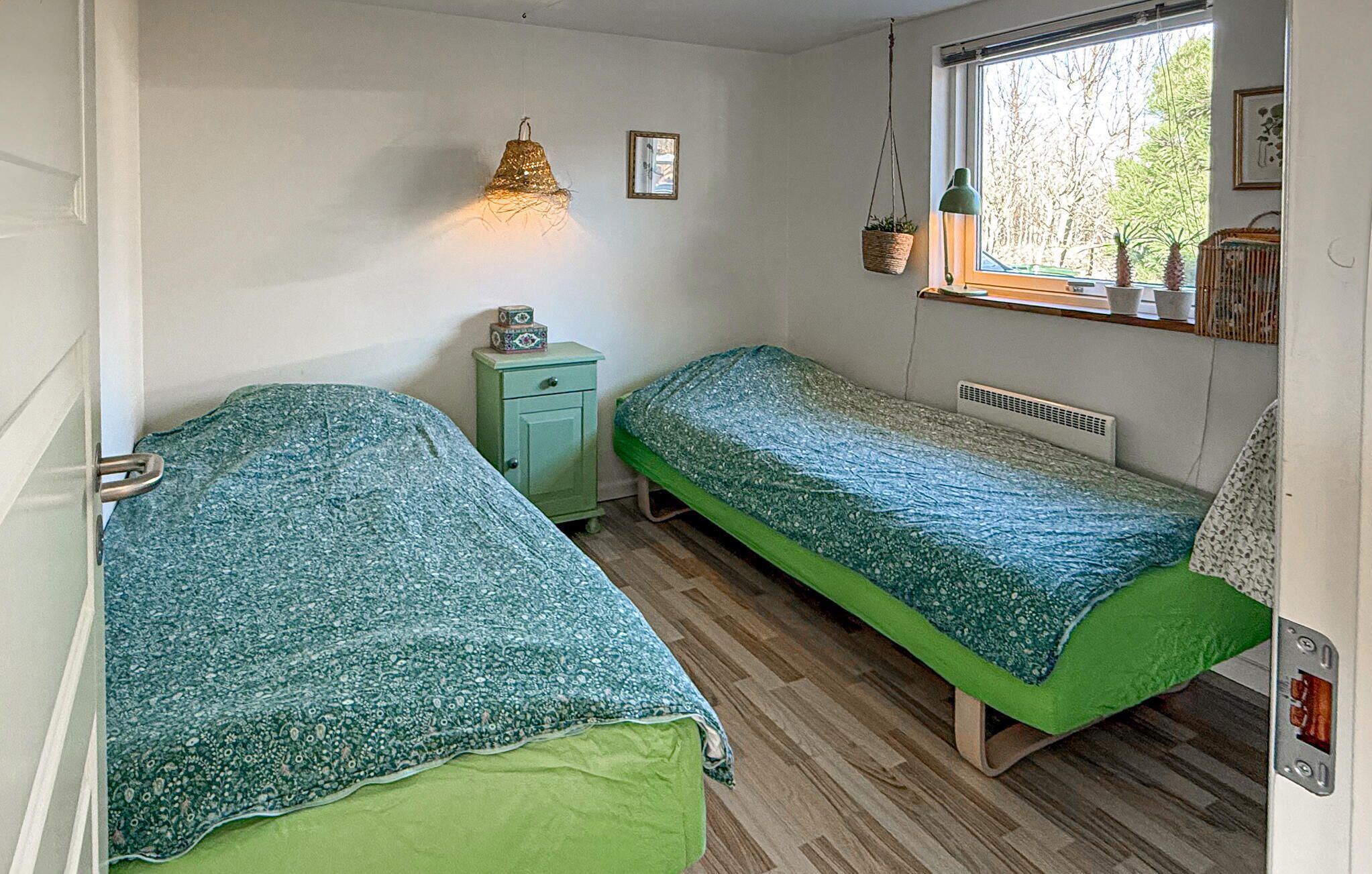 Een compacte, eenpersoonskamer met twee enkele bedden, een raam met uitzicht, een nachtkastje en een hanglamp.