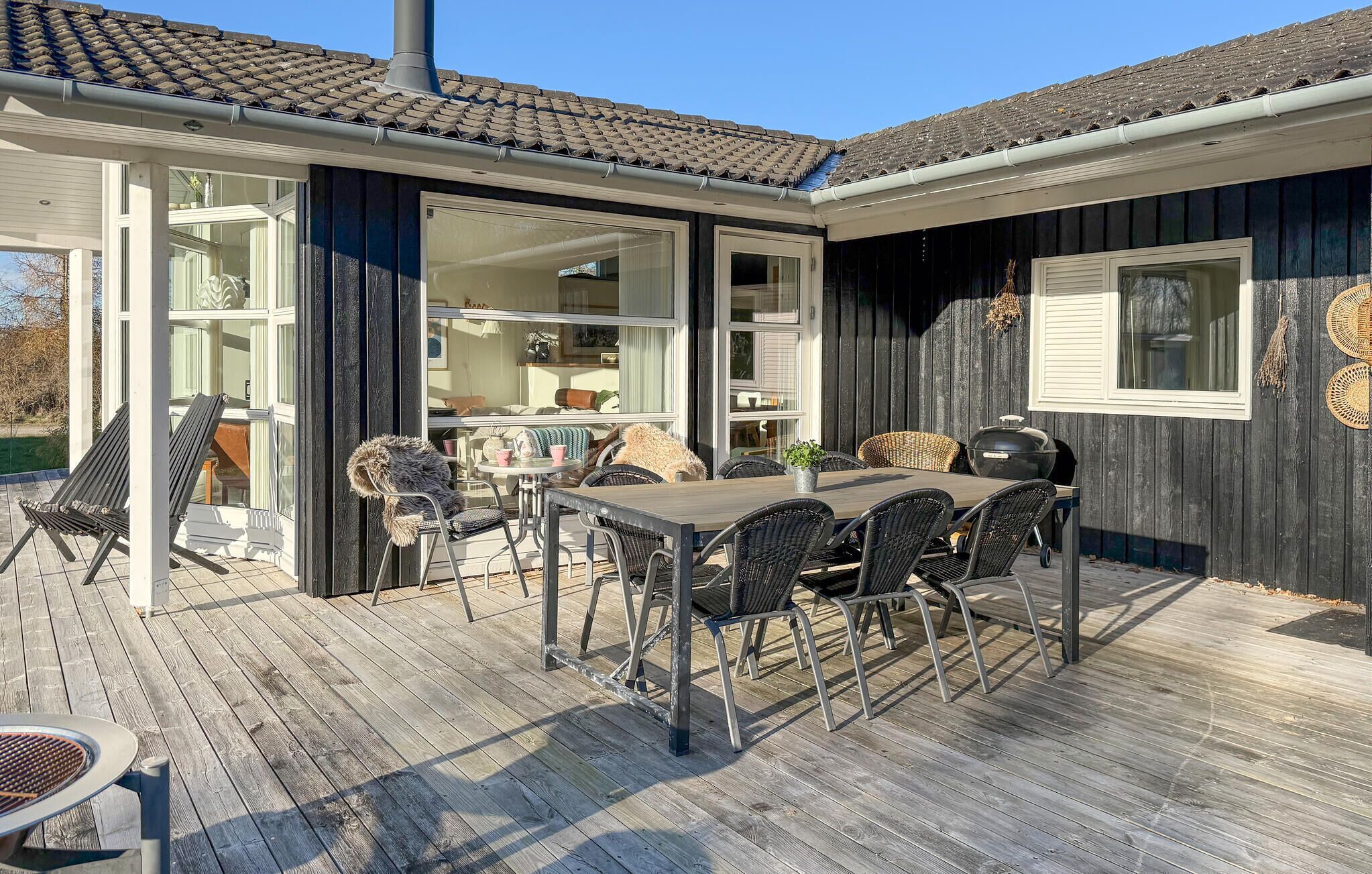 An outdoor patio with a table and chairs, a grill, and a dog.