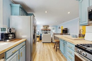 A kitchen with light blue cabinets, a wooden countertop, a stove, and a refrigerator.