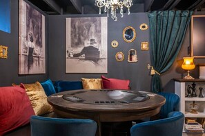 A room with a round table, blue chairs, a chandelier, and wall art. - Luxe Historic Gem: Hidden Game Rm, Hot Tub, Sauna (Lee's Summit)